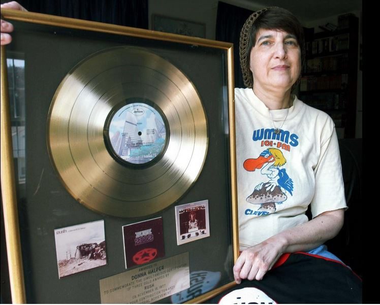 Donna Halper holding the gold record celebrating millions of Rush albums sold